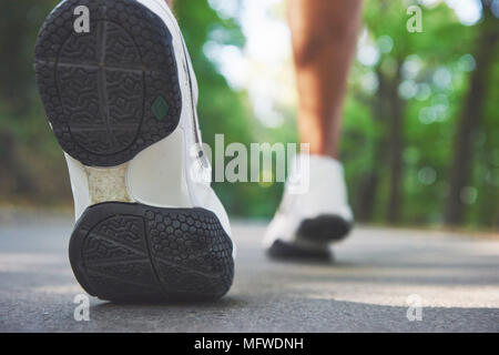 Outdoor Langlauf im Konzept laufen für Training, Fitness und gesunde Lebensweise. In der Nähe der Füße von junger Läufer Mann entlang der Straße im Park läuft Stockfoto
