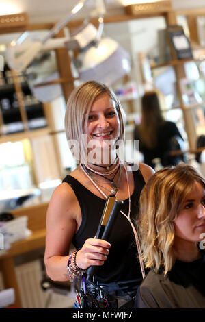 Ein Friseur dargestellt an einem jungen Mädchen die Haare zu einem Friseure in Chichester, West Sussex, UK. Stockfoto