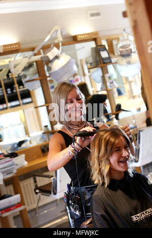 Ein Friseur dargestellt an einem jungen Mädchen die Haare zu einem Friseure in Chichester, West Sussex, UK. Stockfoto