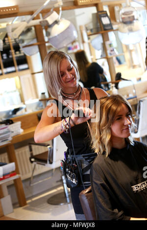 Ein Friseur dargestellt an einem jungen Mädchen die Haare zu einem Friseure in Chichester, West Sussex, UK. Stockfoto