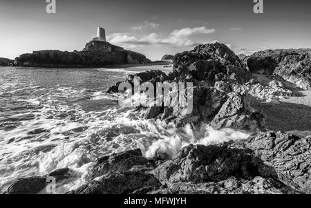 Wellen auf felsigen Strand mit alten lighhouse auf Felsen im Hintergrund. Ynys LLanddwyn im Nordwesten Anglessey, Wales, Großbritannien Stockfoto