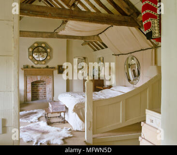 Doppelbett im Schlafzimmer im Landhausstil mit Balkendecke Stockfoto