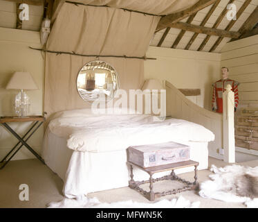 Doppelbett im Schlafzimmer im Landhausstil mit Balkendecke Stockfoto