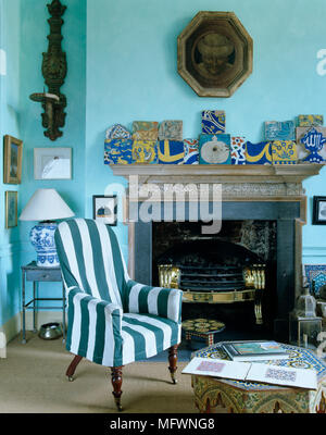 Sessel mit blauen Streifen Abdeckung vor dem Kamin im traditionellen Stil in Blau Wohnzimmer Stockfoto