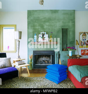 Modernes Wohnzimmer mit Kamin in der grünen Wand gesetzt, Stapel von blue Kissen, Stockfoto