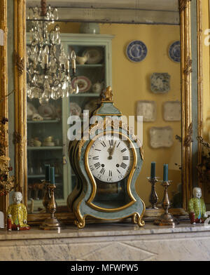 In der Nähe von antiken carriage Clock am Kaminsims mit Ornamenten vor Spiegel mit Reflexion der Kronleuchter Stockfoto