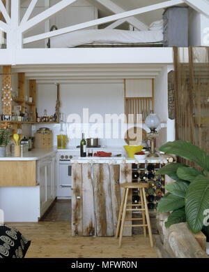 Küche mit Treibholz an der Vorderseite des Frühstück Bar angeschlossen ist neben Wein Halter vor Geräte und gefliesten Wand Stockfoto
