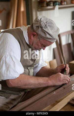 Schreiner in authentischen frühen amerikanischen Kleidung in seinem Geschäft durch seine authentische Werkzeuge in Colonial Williamsburg Virginia Umgeben arbeiten Stockfoto