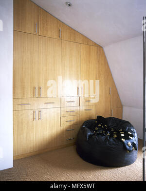 Modernes Schlafzimmer mit Teppichboden, sitzsack, Kissen, und eine Wand aus Holz, Einbauschrank. Stockfoto