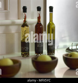 Countertop Detail mit Äpfeln in hölzernen Schüsseln und drei Flaschen verschiedene Öle und Essige. Stockfoto