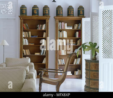 Paar Sesseln vor Töpfen auf hölzerne Bücherregale angezeigt Stockfoto