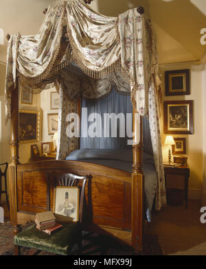 Holz- Himmelbett mit opulenten Vorhängen Stockfoto