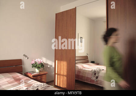Frau verlassen Schlafzimmer mit Kleiderschrank und Ganzkörperspiegel. errichtet wurde. Stockfoto