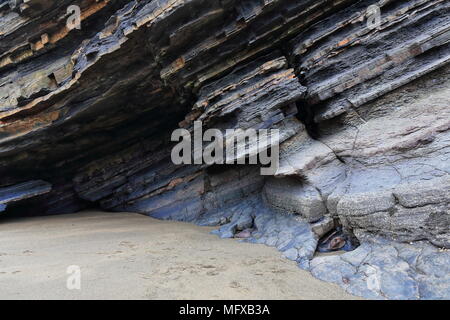 Rock Shelter unter gekippt flysch Schichten - Fuß Gaztelugatxe Insel in Spanien. s Baskenland - real life Lage mit in TV-Serien Spiel der Throne Stockfoto