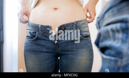 Nahaufnahme der Jungen beleibte Frau setzen auf enge Jeans im Ankleidezimmer Stockfoto