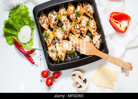 Italienische Pasta Conchiglioni Rigati gefüllt mit Käse und Fleisch auf weißem Holz Tisch. Ansicht von oben. Stockfoto