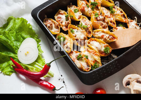 Italienische Pasta Conchiglioni Rigati gefüllt mit Käse und Fleisch auf weißem Holz Tisch Stockfoto