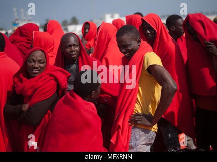 Migranten Chats, wie sie an Bord eines spanischen Küstenwache Schiff steht. Eine Gruppe von Migranten gerettet aus einem beiboot im Mittelmeer im Hafen von Málaga angekommen. An Bord vom Boot aus, Mitgliedern des spanischen Maritimen Sicherheit Rettung Insgesamt 80 Migrantinnen in der Nähe der Küste von Malaga, davon sind 6 Frauen und 4 Kinder. Stockfoto
