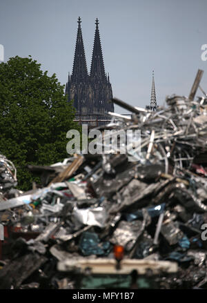 27 April 2018, Deutschland, Köln: die Türme des Kölner Doms kann hinter einem Hügel von Schrott in den Räumlichkeiten eines Junk Yard zu recicyling alte Metalle im Hafen in Deutz widmet. Foto: Oliver Berg/dpa Stockfoto