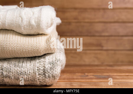 Stapel von gemütlichen warmen Pullover gestrickt, Holz- Hintergrund. Weiß Pullover im Retro Style. Stockfoto