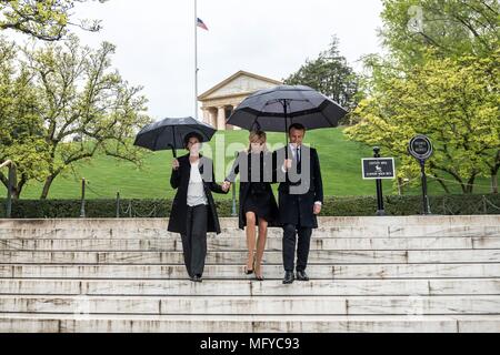 Der französische Präsident Emmanuel Längestrich, rechts, und seine Frau Brigitte Längestrich, sind durch Superintendent Katharine Kelley begleitet, links, bei einem Besuch der Grabstätte des früheren Präsidenten John F. und Jacqueline Bouvier Kennedy Onassis an einem regnerischen Tag auf dem Arlington National Cemetery April 24, in Arlington, Virginia, 2018. Stockfoto