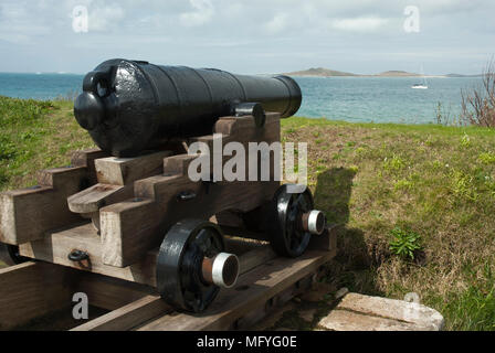 Alte Kanone von König Charles Batterie unter die Sterne Schloss, Meer mit Samson Insel und einer Yacht in der Entfernung. St Marys, Scilly, Stockfoto