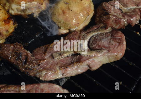 Schweinefleisch Steaks und Hühnerschenkel Kochen auf dem Außen BBQ Grill Stockfoto