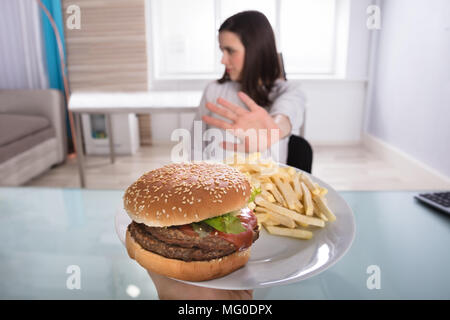 Junge Frau ablehnen, Burger und Pommes frites auf Platte Stockfoto