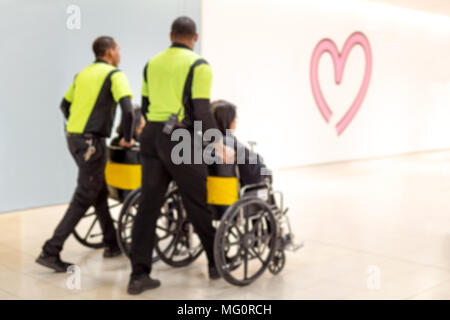 Verschwommenes Konzept Hausmeister drücken ältere Menschen im Rollstuhl im Flughafen Stockfoto