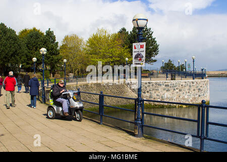 26. April 2018 eine 94-jährige Seniorin auf einer Behinderung Roller an der Küste in Bangor Northern Ireland an einem kalten, aber hell und Stockfoto