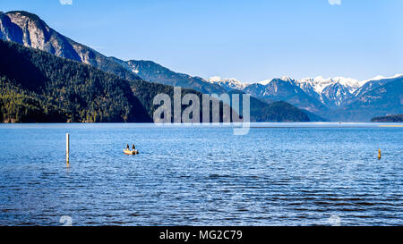 Angeln auf Pitt See mit den schneebedeckten Gipfeln des Goldenen Ohren gellen Peak und andere Gipfel der Coast Mountains in Brritish Columbia Stockfoto