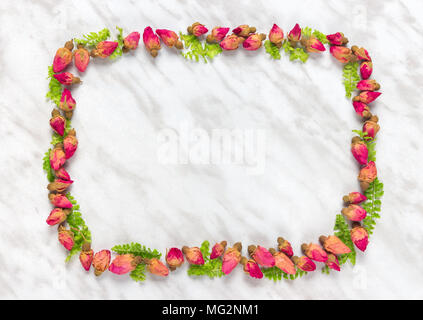 Rahmen aus getrockneten Rosen und grünen Blättern, auf Marmor Hintergrund. Stockfoto