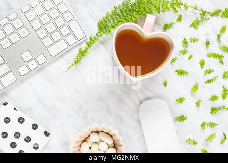 Schöne moderne Home Office Arbeitsbereich mit Herzförmigen Teetasse. Flach Zusammensetzung auf Marmor Hintergrund, mit Kopie Raum im Zentrum. Stockfoto