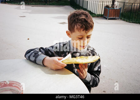 Acht Jahre alten Jungen essen ein lángos, eine ungarische fritierten Fladenbrot. Tiergarten Schönbrunn, Maxingstraße, Wien, Österreich, Europa. Stockfoto