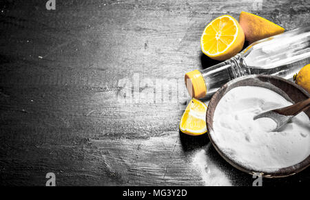 Backpulver in eine Schüssel geben und mit Essig und Zitronenscheiben. Auf der schwarzen Tafel. Stockfoto