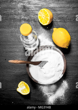 Backpulver in eine Schüssel geben und mit Essig und Zitronenscheiben. Auf der schwarzen Tafel. Stockfoto