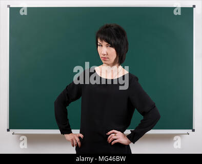 Mädchen Lehrer durch Chalk Board posiert, Lernkonzept, grüner Hintergrund, Studio shot Stockfoto