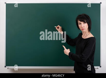 Strenge Lehrer durch Chalk Board posiert, Lernkonzept, grüner Hintergrund, Studio shot Stockfoto