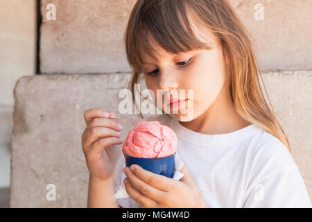 Kleine blonde Europäische Mädchen isst rosa Eis, bis Outdoor Portrait schließen Stockfoto