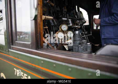 Nahaufnahme des Dampfzugtreibers isoliert in der Motorkabine auf Fußplatte der Vintage UK Dampflokomotive an den Kontrollen. Dampfzüge Großbritannien. Stockfoto