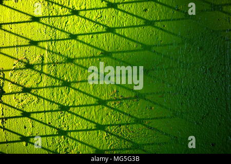 Metall Zaun Schatten auf grünem Beton Wand Hintergrund. Stockfoto