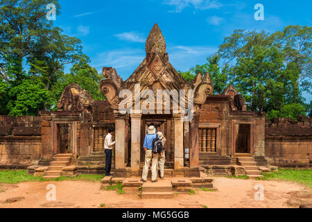 Touristen bewundern die East gopura des zweiten Gehäuse mit dem erstaunlichen geschnitzten Giebel aus rotem Sandstein in der Kambodschanischen Banteay Srei Tempel. Stockfoto