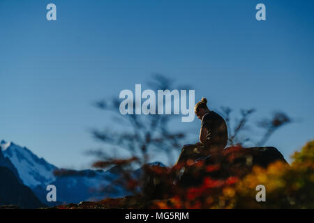 Mann sitzt auf den Felsen und denken während des Sonnenuntergangs im Nationalpark Los Glaciares Nationalpark. Herbst in Patagonien, der Argentinischen Seite Stockfoto