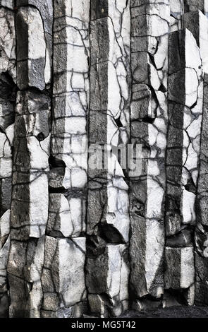 Reynisfjara, South Island. Der schwarze Sandstrand ist eine berühmte Touristenattraktion, wie sind die regelmäßigen Basalt Felsformationen durch vulkanische Aktivität gebildet Stockfoto