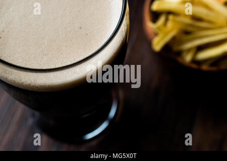 Dunkles Bier mit Snacks Potato Chips auf Holz- Oberfläche. Beverage Konzept. Stockfoto