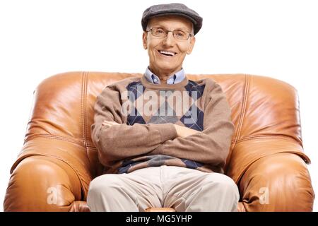 Senior in einem Ledersessel auf weißem Hintergrund lächelnd sitzt Stockfoto