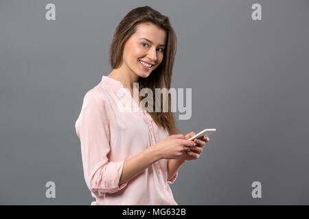 Fröhliche junge Frau mit ihrem Smartphone Stockfoto