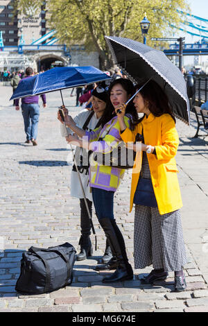 London, Großbritannien - 23 April, 2015: Drei Damen nehmen eine selfy beim Tragen von Sonnenschirmen an einem sonnigen Tag in London neben dem Tower von London. Stockfoto