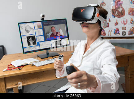 Symbolische Foto von Telemedizin, einer Ärztin in einer Arztpraxis, mit VR-Brille, Virtual Reality, 3D-Darstellung eines MRI, kommuniziert wit Stockfoto