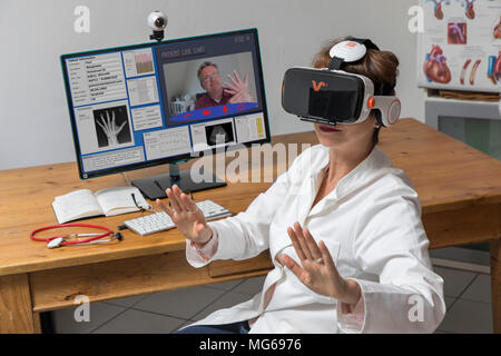 Symbolische Foto von Telemedizin, einer Ärztin in einer Arztpraxis, mit VR-Brille, Virtual Reality, 3D-Darstellung eines MRI, kommuniziert wit Stockfoto
